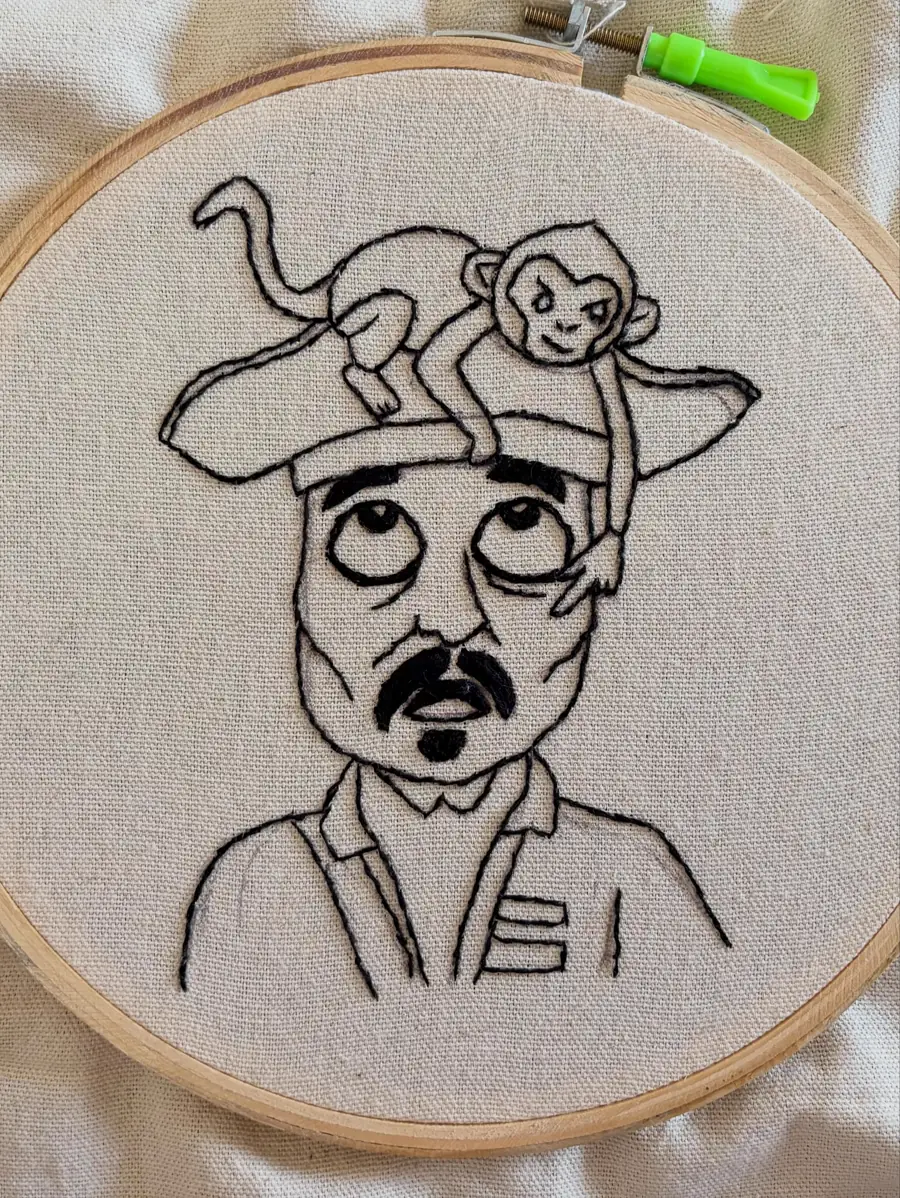 Black backstitch outline, one of the basic embroidery stitches, stitched on fabric in a hoop